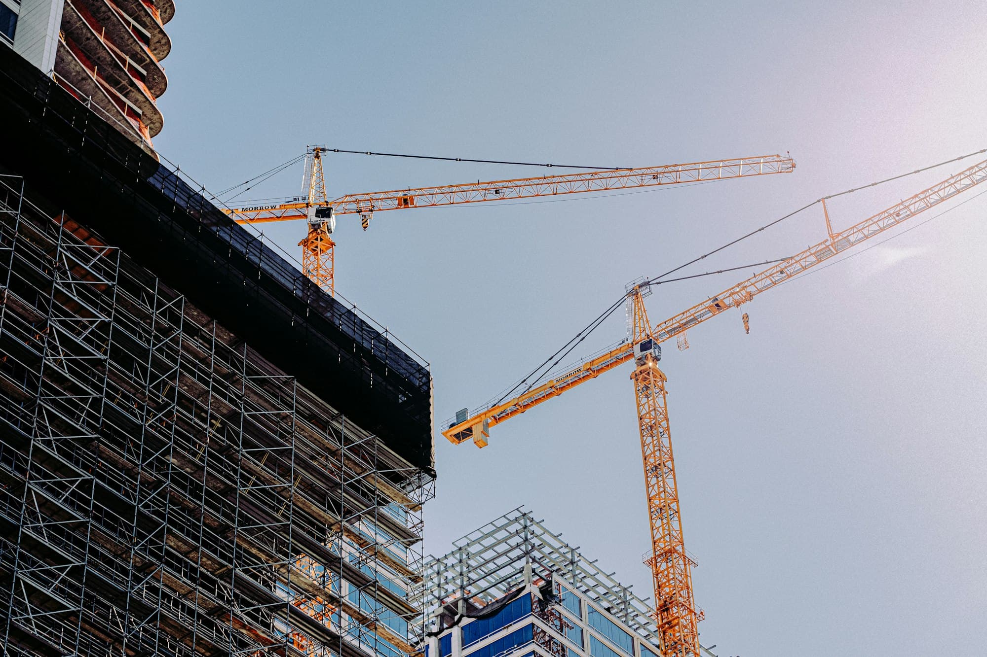 High-rise under construction with two tower cranes.